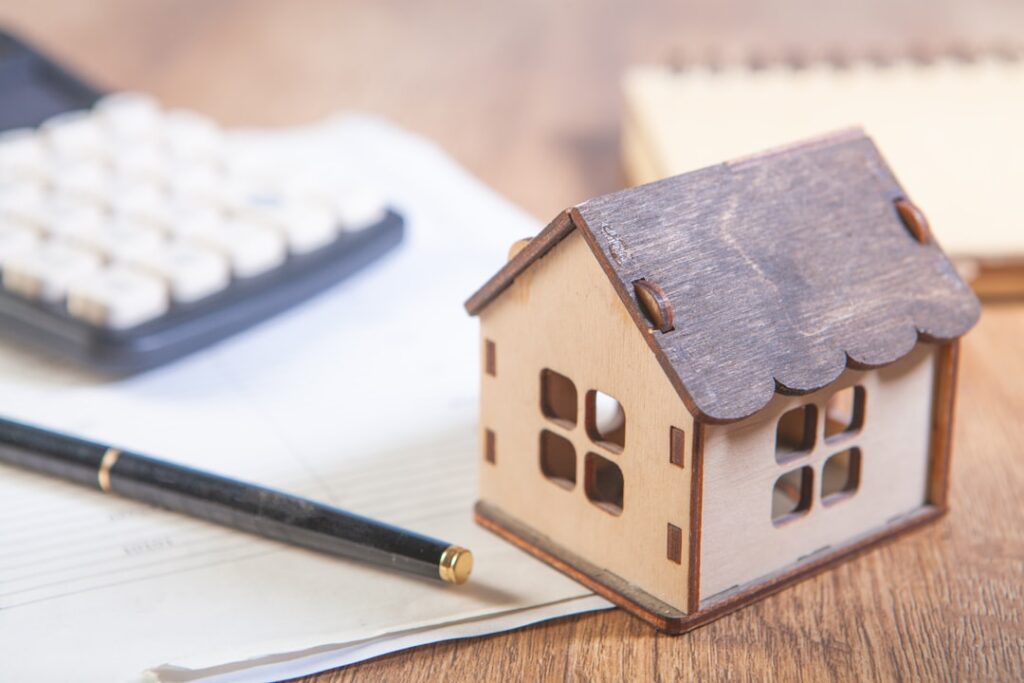 Model house with calculator and pen on desk.